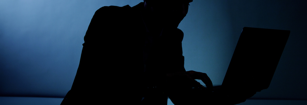 Man Using Computer in Shadows