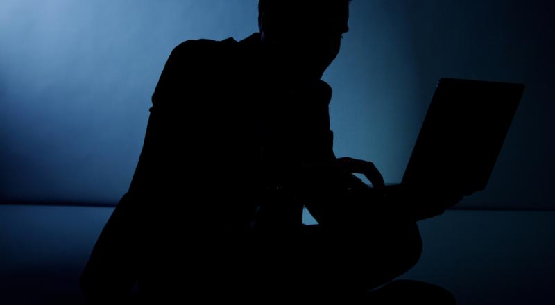 Man in Shadow Working on Computer